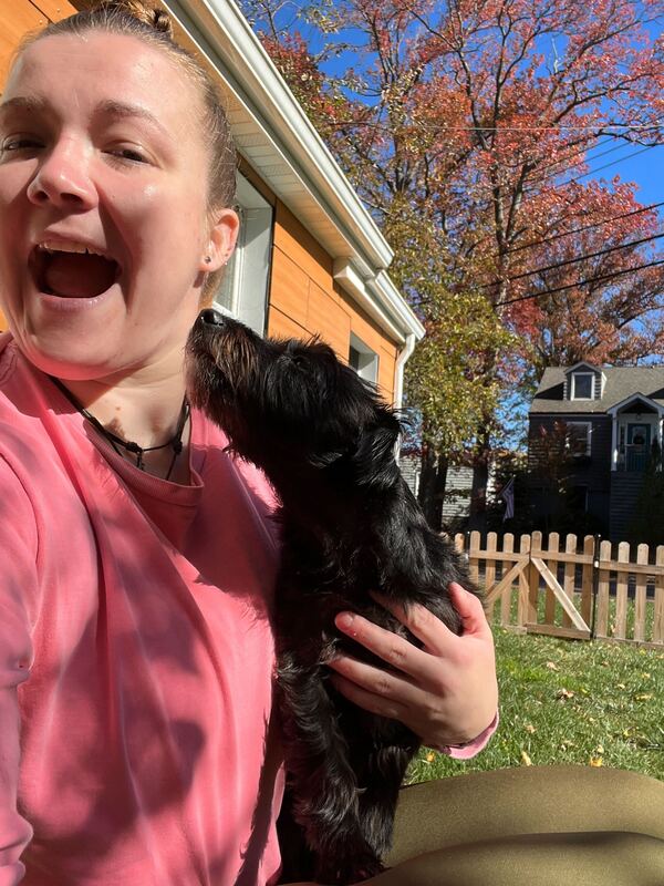 Community member holding a small black dog